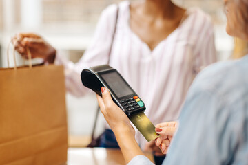Unrecognizable store owner swiping a credit card while serving a customer