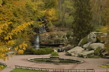 Obraz premium Beautiful autumn park with rocks, pond and cave.