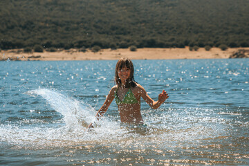 Happy little girl with the waves on the lake on a sunny day.