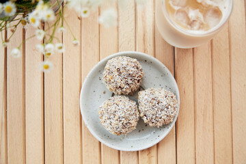 Healthy vegan handmade sweets - gluten and sugar free natural hedgehogs and ice late coffee on the wooden table close up. Healthy dessert