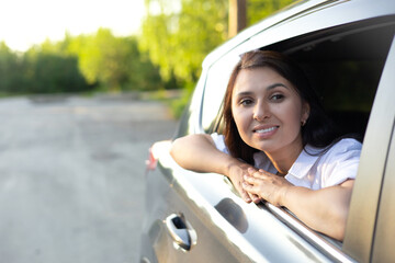 Travel, vacation. A young beautiful woman sits in a car and smiles, looking into the distance. Lifestyle