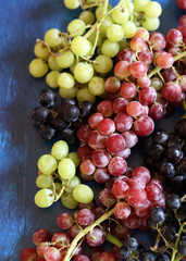 Black, green and red grapes on close up.  Top view photo of seasonal fruits. Healthy eating concept. 