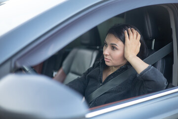 A young tired woman behind the wheel of a car. City traffic jam on the road. Stress, traffic.