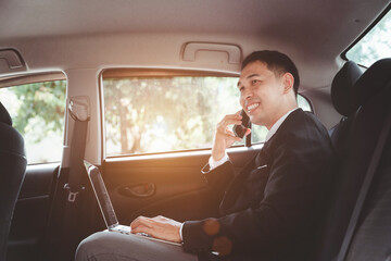 Confident asian businessman using mobile smart phone while sitting in the car.