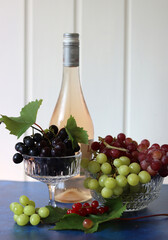 Still life with wine and grapes. Colorful photo of bottle of rose wine and different sorts of...
