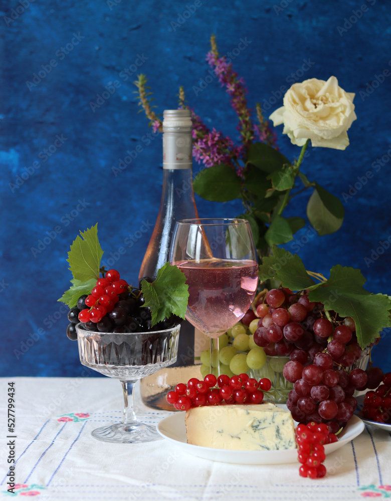 Wall mural Grapes, wine and cheese on a table. Colorful summer still life on textured background with copy space.