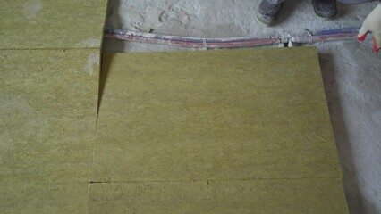 The builder insulates the floors of the house with glass wool. Laying glass wool on a concrete floor.