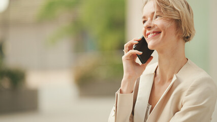 Close up, smiling businesswoman with blond hair talking on cellphone