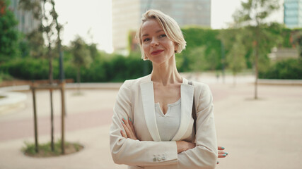 Businesswoman crosses her arms, looks at the camera - obrazy, fototapety, plakaty