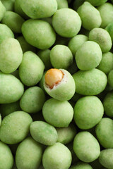 Tasty wasabi coated peanuts as background, top view