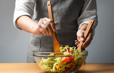 Woman making tasty salad with Chinese cabbage at wooden table, closeup