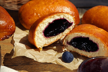Delicious baked patties with jam and blueberries on wooden table, closeup