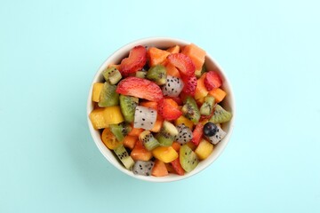 Delicious exotic fruit salad on turquoise background, top view