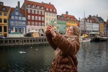 Fototapeta na wymiar A tourist takes a selfie while in Nyhavn canal in the Danish capital, Denmark tourism concept.