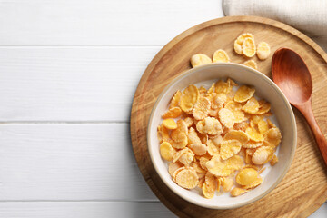 Tasty cornflakes with milk served on white wooden table, top view. Space for text