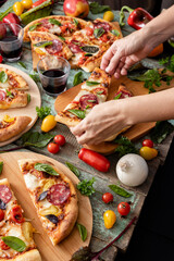 Pizza ready to eating, woman hands hold pizza piece, cutted pizza with fresh vegs and greens