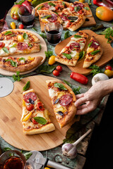 Tomatoes pizza party, woman hand hold the pizza piece vertical view