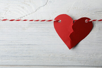 Broken red paper heart and rope on white wooden background. Relationship problems concept