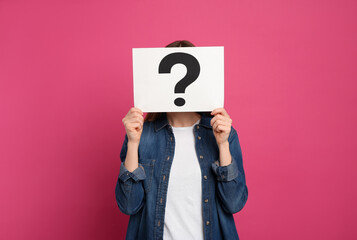 Woman holding question mark sign on pink background