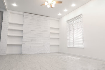 Empty room with textured wall, stylish wooden shelves and large window