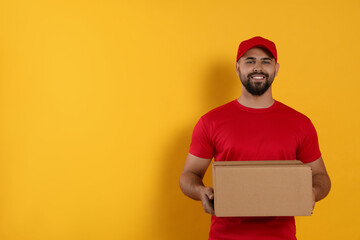 Courier holding cardboard box on yellow background, space for text