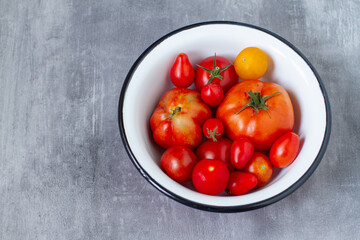 Different varieties of garden tomatoes in rustic metal bowl