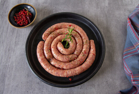 Homemade raw sausages on a dark plate, view from above