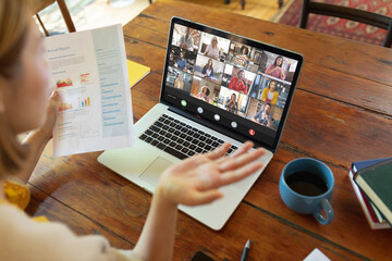 Asian businesswoman briefing report to colleagues during video conference through laptop in office