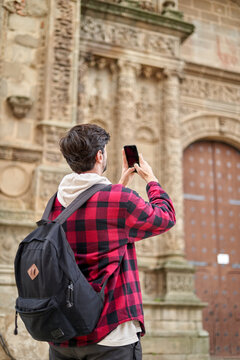 Faceless tourist taking photo of old building