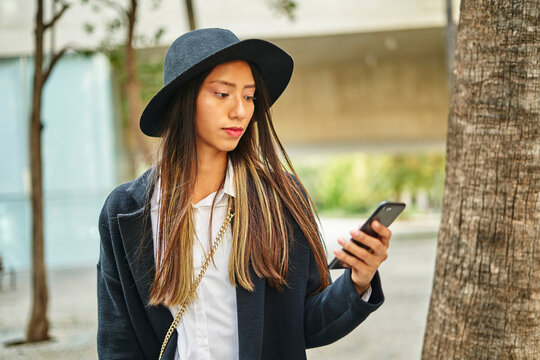 Focused Hispanic woman browsing smartphone