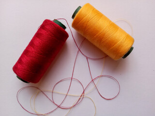 spools of thread, red and yellow threads on a white background, sewing tools