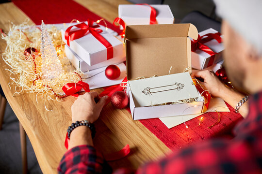 DIY, Man in Santa hat making greeting card for New Year and Christmas for friends or family , packing presents or gifts, mail manager concept.