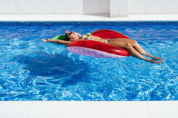 Relaxed woman sunbathing on inflatable ring in pool