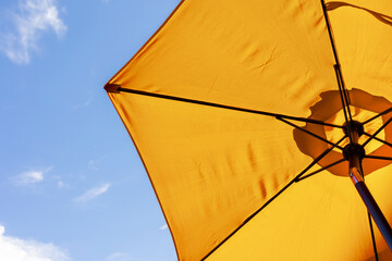 bright yellow beach umbrella from below, vivid yellow and blue sky