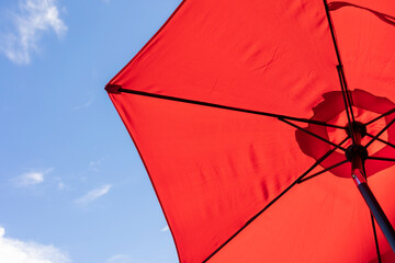 bright red beach umbrella from below, vivid red and blue sky