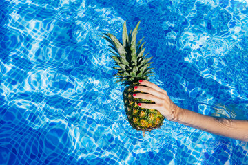 Woman with pineapple resting in pool
