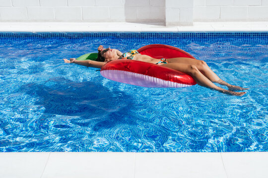 Relaxed woman sunbathing on inflatable ring in pool