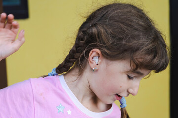 Girl with a warming therapeutic cotton swab in the ear with a sad and tearful face is holding her...