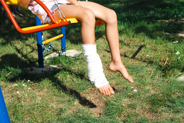 Children's legs are bandaged in plaster - barefoot on a swing. Traumatic equipment, child injury,...