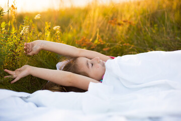 Girl sleeps on bed in grass, Sweet stretches and yawns sleepily, good morning in fresh air....
