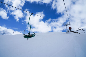 Fototapeta na wymiar Chiarlift or ski lift in snow mountains in winter day, slopes and sky with clouds