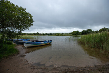 Fototapeta na wymiar paysage d'Irlande, vue sur un lac. Des petites barques sont amarrées et flottent paisiblement