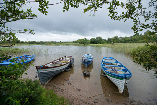 paysage d'Irlande, vue sur un lac. Des petites barques sont amarrées et flottent paisiblement