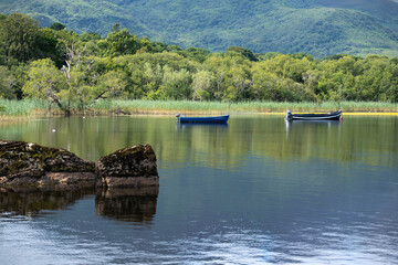 paysage d'Irlande, vue sur un lac. Des petites barques sont amarrées et flottent paisiblement