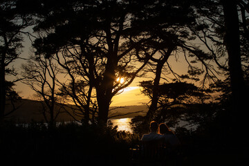 un couple d'amoureux contemple un magnifique coucher de soleil sur un lac