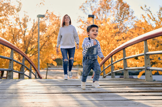 Happy child and mother on bridge in park