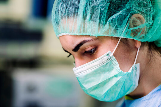 Crop female surgeon in mask and surgical cap during operation