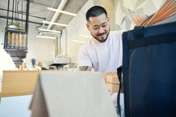 Joyous young man getting food ready to be delivered from cafe