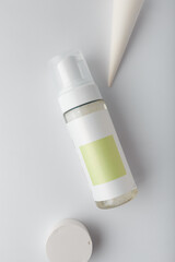 Cosmetics mock up template, bottle of washing foam with blank label, concrete decor on white background. Face skin care cleanser, top view