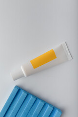 Cosmetics mockup tube with bright blank label. Cream with fruit, berry, herbal vitamin extract on white with concrete decor. Copy space, vertical